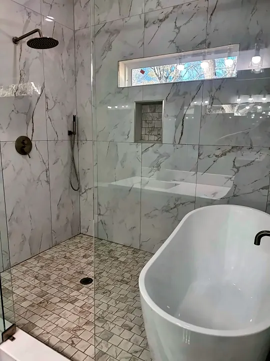 Walk-in marble shower with clear glass after cleaning