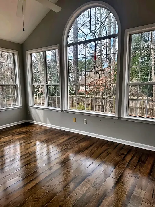 Sunroom with arched windows and glossy hardwood floors after cleaning