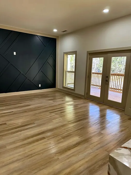 Empty room with a dark accent wall and shining floors, ready for move-in