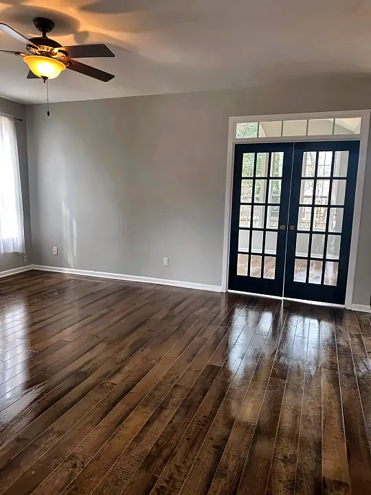 Empty room with dark hardwood floors and French doors after cleaning