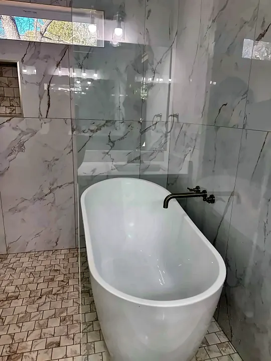 Freestanding soaking tub in a marble bathroom, spotless