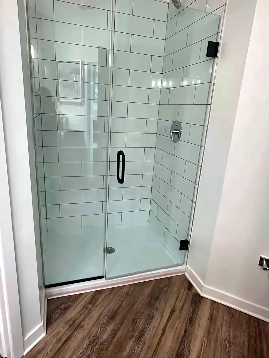 Glass shower enclosure with white subway tile after cleaning